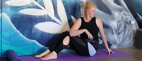 Remedial stretch therapist Holly Hicks sitting on a yoga mat and doing a seated twist