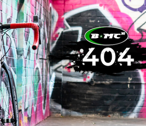 A titanium bicycle leaning against a graffitied wall, a BMCR 404 Page Not Found message next to it