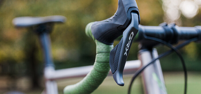 Shimano GRX shifter detail on a custom Bossi Grit SX bicycle, contrasting with the green Ciclovation handlebar tape